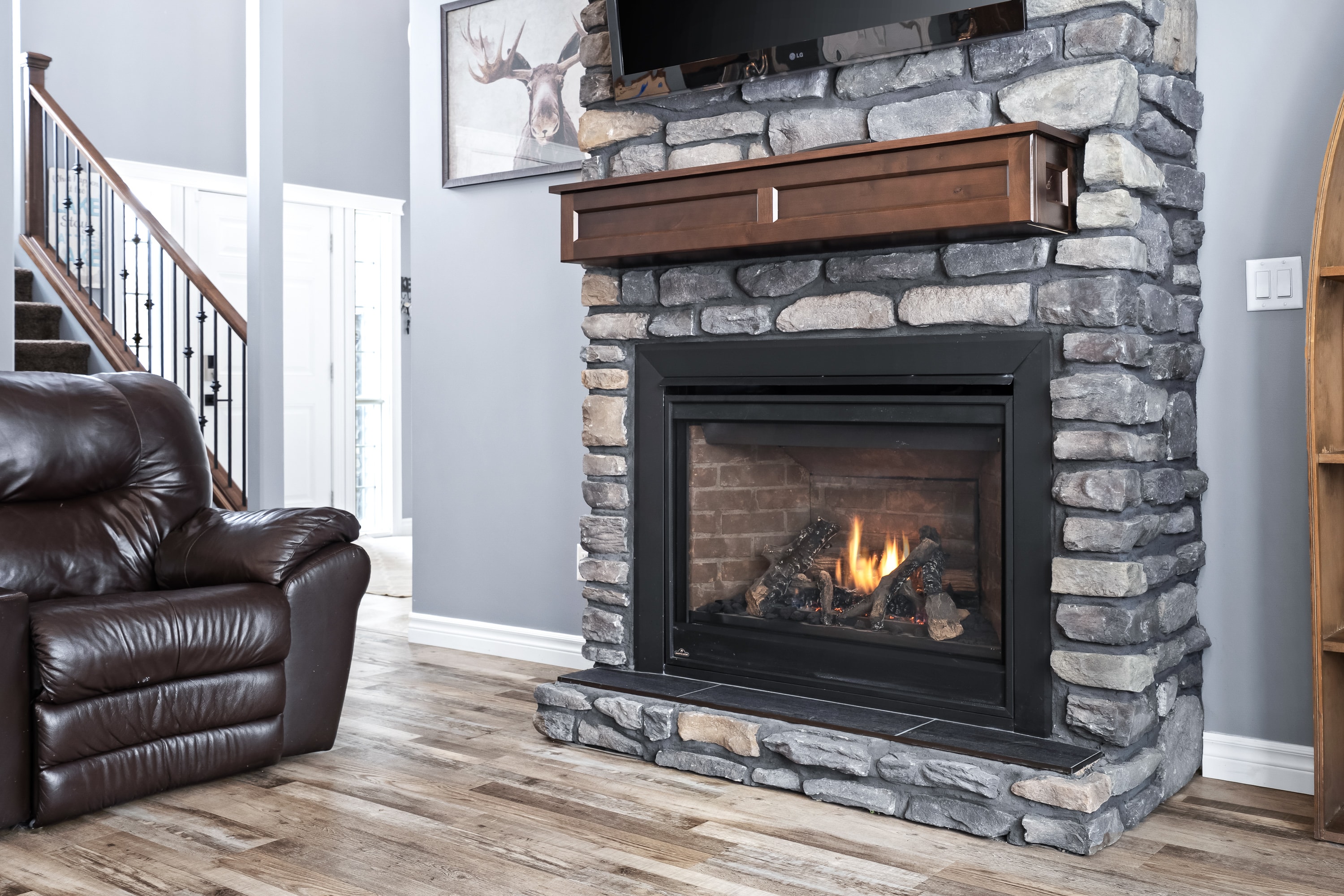 Lake house living room with stone fireplace and staircase